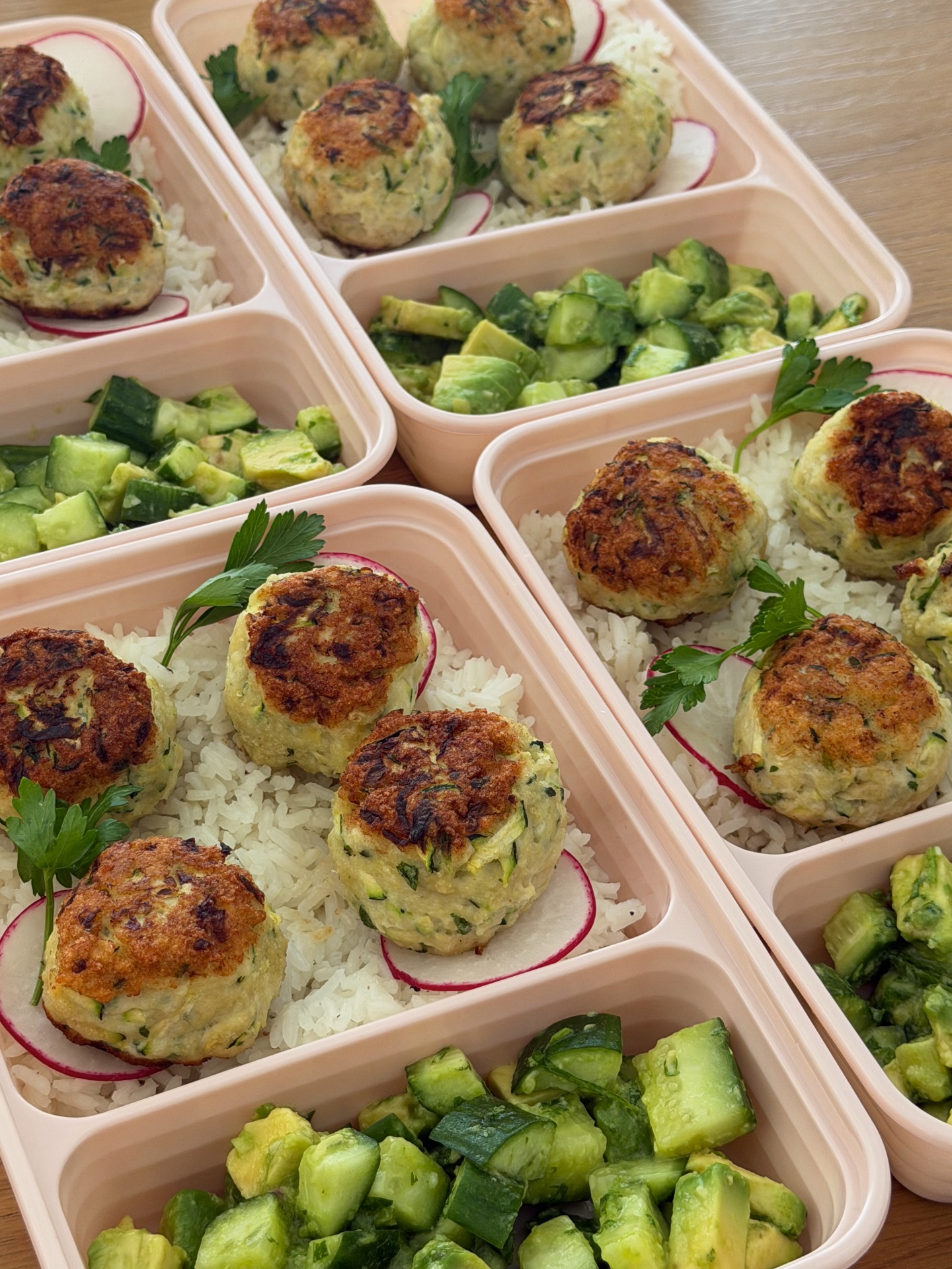 Zucchini chicken meatballs with garlic rice and cucumber avocado salad in meal prep containers